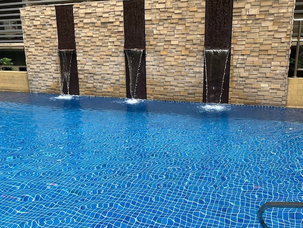 Una piscina al aire libre, sillones reclinables de piscina