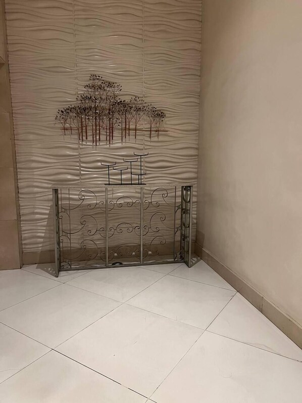 Rincón de una habitación con un panel decorativo y una reja de metal.
