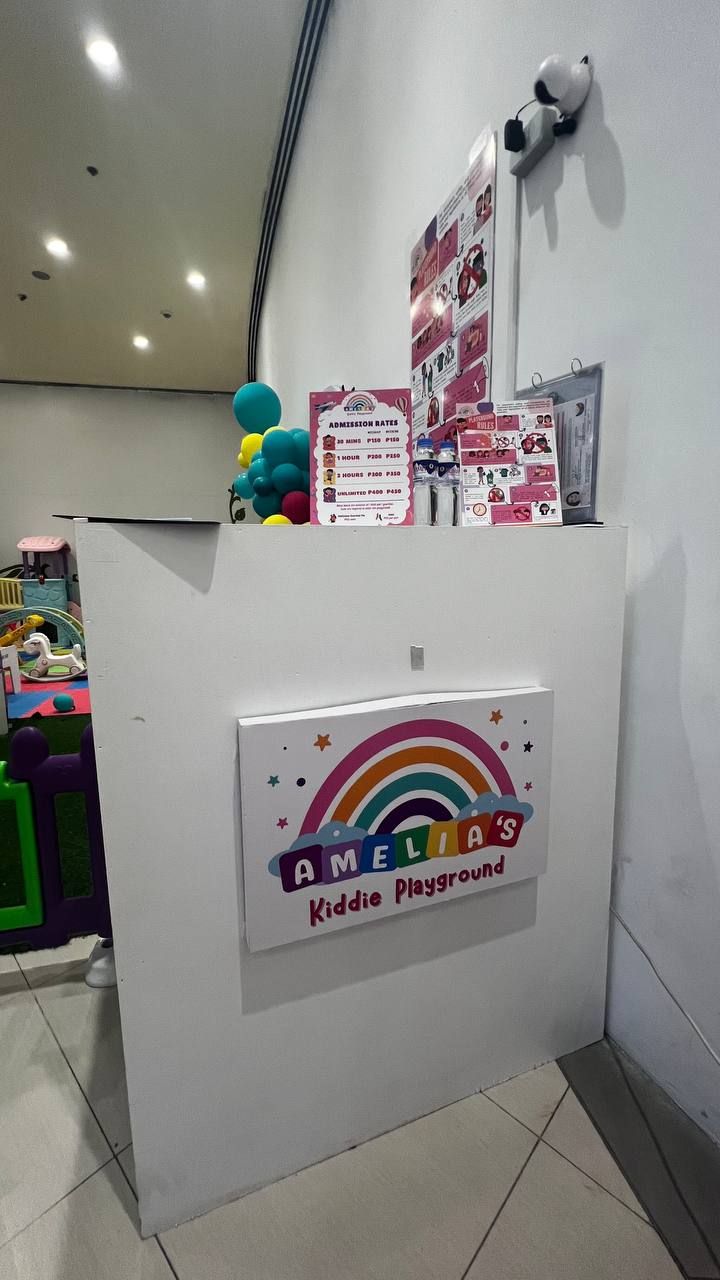 A play area with a sign for 'Amelia's Kiddie Playground' and admission rate posters.