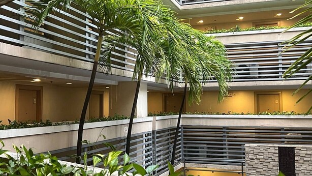 Un atrio de varios niveles con una fuente central, balcones con barandillas y plantas de interior.