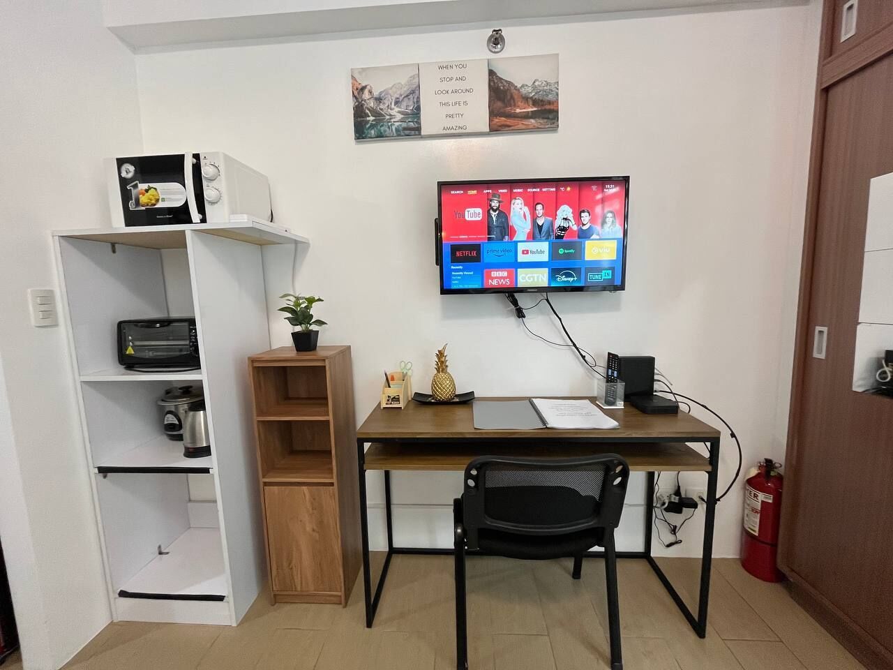 A compact office space with a desk, chair, and a mounted TV displaying various streaming services.