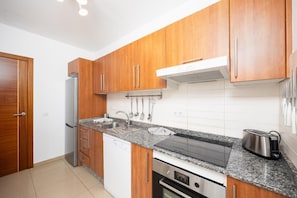 A modern kitchen with wooden cabinets, a stainless steel sink, and a built-in oven.