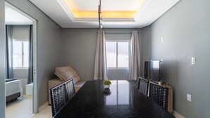 A modern dining area with a black granite table, cushioned chairs, and a small potted plant. - Apts Near the Beach w/ Full Amenities - RNC (Florianópolis)