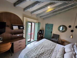 Un dormitorio con cama, escritorio, silla, armario y puerta que da a un espacio exterior.