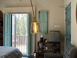Une chambre avec un lit, une table avec une machine à café, une télévision et une porte donnant sur l’extérieur.