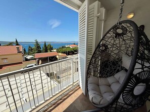 Ein Balkon mit einer Hängematte, Blick aufs Meer und Gebäude im Hintergrund.
