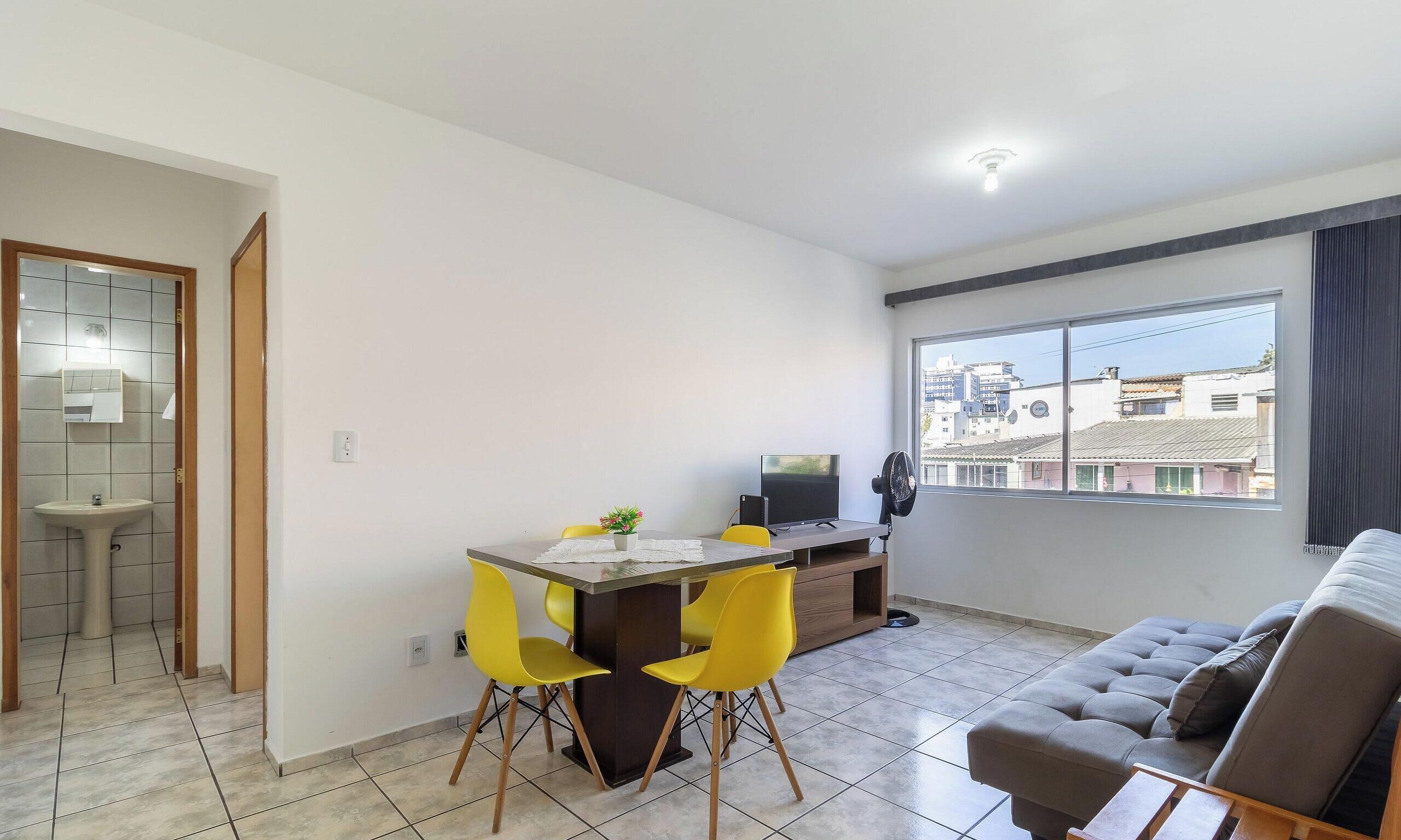 A modern living space with a dining area, a sofa, and a TV.