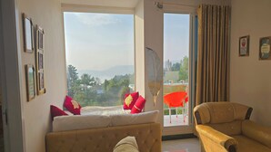 Una habitación con cama, sofá y balcón con vistas a las montañas.