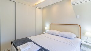 A modern bedroom with a large bed, white linens, a grey blanket, and a white towel. - Beautiful 2 Bedroom Apartment in Itacorubi Rlz0301 (Florianópolis)