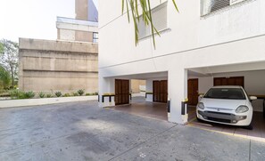 A modern building with a white exterior, a concrete ground floor, and a white car parked inside.