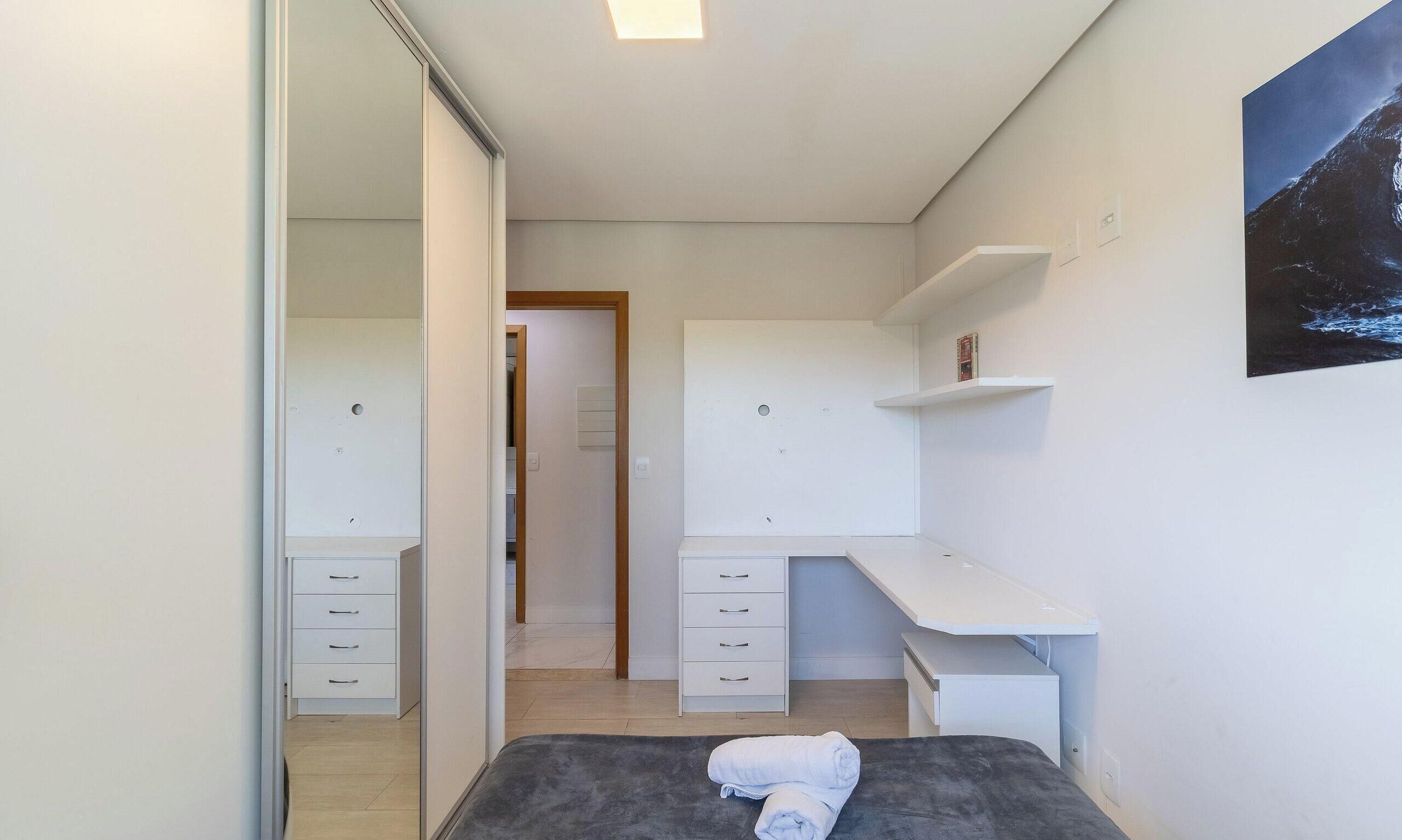 Ein modernes Schlafzimmer mit Bett, Kleiderschrank, Schreibtisch und angrenzendem Badezimmer.