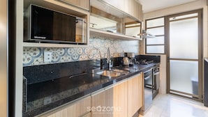 Uma cozinha moderna com micro-ondas embutido, eletrodomésticos de aço inoxidável e painel de parede decorado.