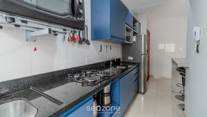 Μια σύγχρονη κουζίνα με γκαζιέρα, φούρνο μικροκυμάτων και μπλε ντουλάπια.