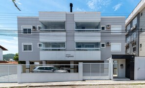 Un immeuble moderne à plusieurs étages, doté d’un toit plat, de grandes fenêtres et d’une voiture garée dans un espace de stationnement couvert.