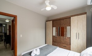 Une chambre à coucher avec un lit, une armoire et un ventilateur de plafond.