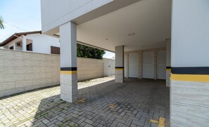 Un espace extérieur abrité, doté d’un sol carrelé, de murs blancs et d’un mur de couleur beige.