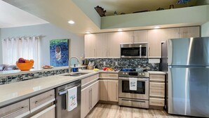 A modern kitchen with stainless steel appliances, wooden cabinets, and a tiled backsplash.