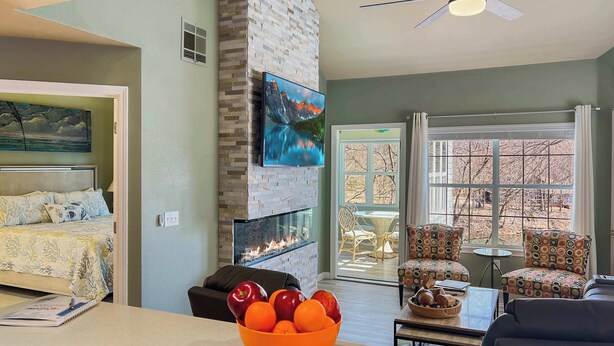 A modern living room with a fireplace, a dining area, and a view of the outdoors.