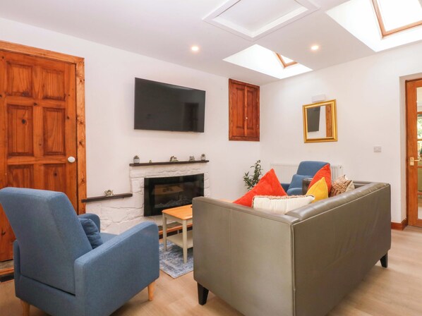 A living room with a fireplace, a flat-screen TV, a sofa, and a blue armchair.