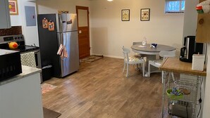 A compact kitchen with a refrigerator, microwave, and stove. There is a dining table with chairs and a small rug. - Trails, Tails & Town – Pet-Friendly Stay Near It All (Helena)