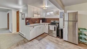 A kitchen with white cabinets, a stainless steel refrigerator, and a tiled backsplash. - Trails, Tails & Town – Pet-Friendly Stay Near It All (Helena)