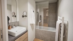 Ein modernes Badezimmer mit einem großen Waschbecken, einer Duschkabine und einem Spiegel.