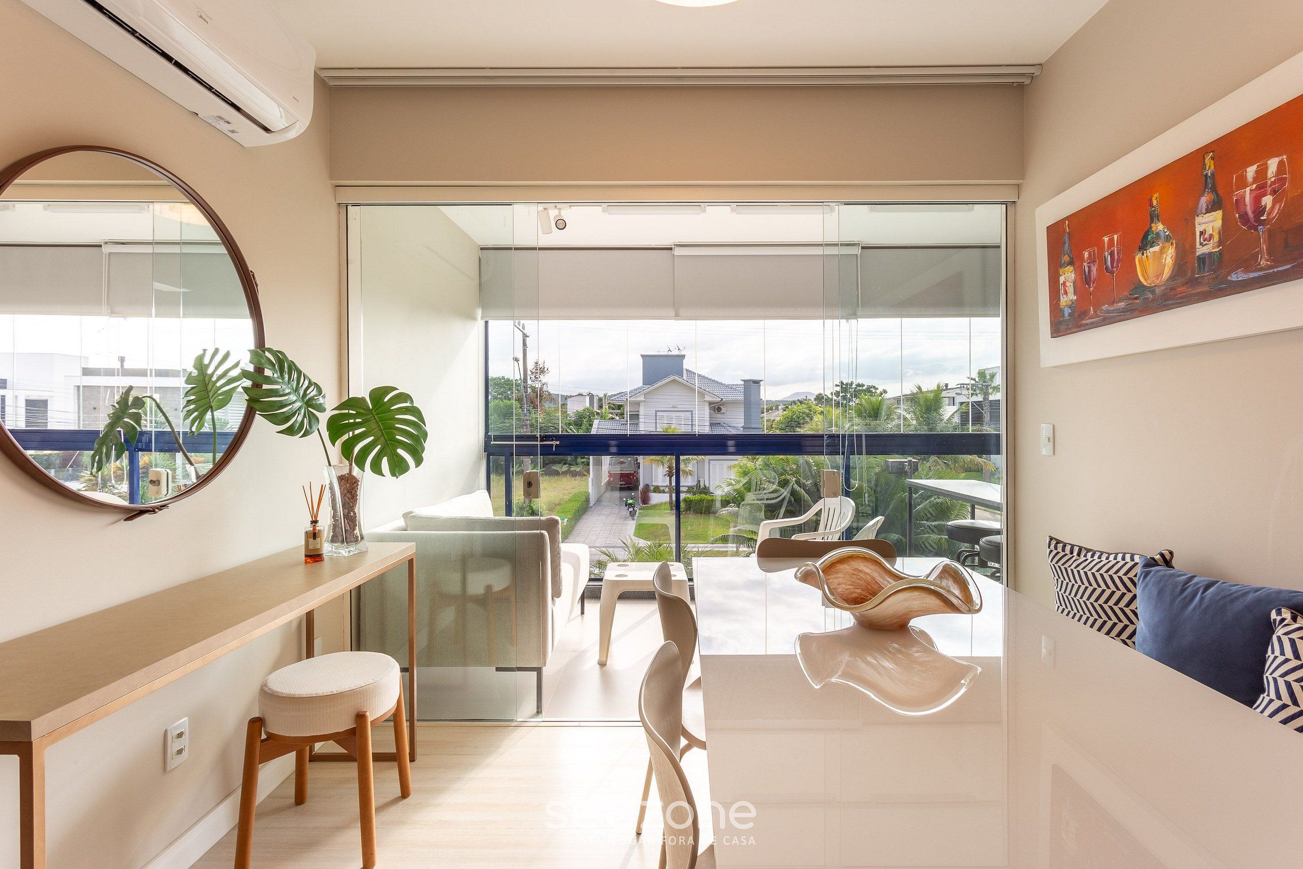 Un salon moderne avec une porte vitrée donnant sur un balcon, un coin repas et une vue sur une rue résidentielle.