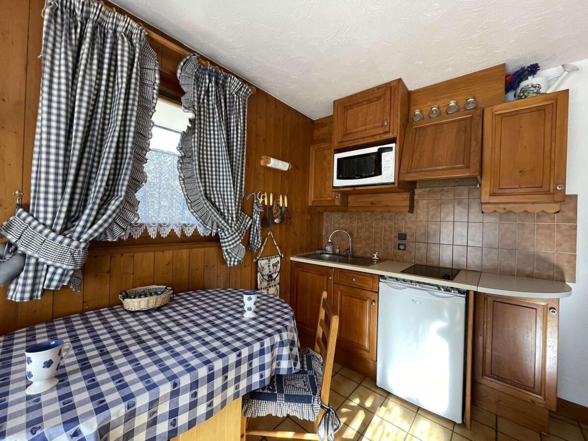 Eine kompakte Küche mit Holzausstattung, einer Mikrowelle und einem kleinen Spülbecken.