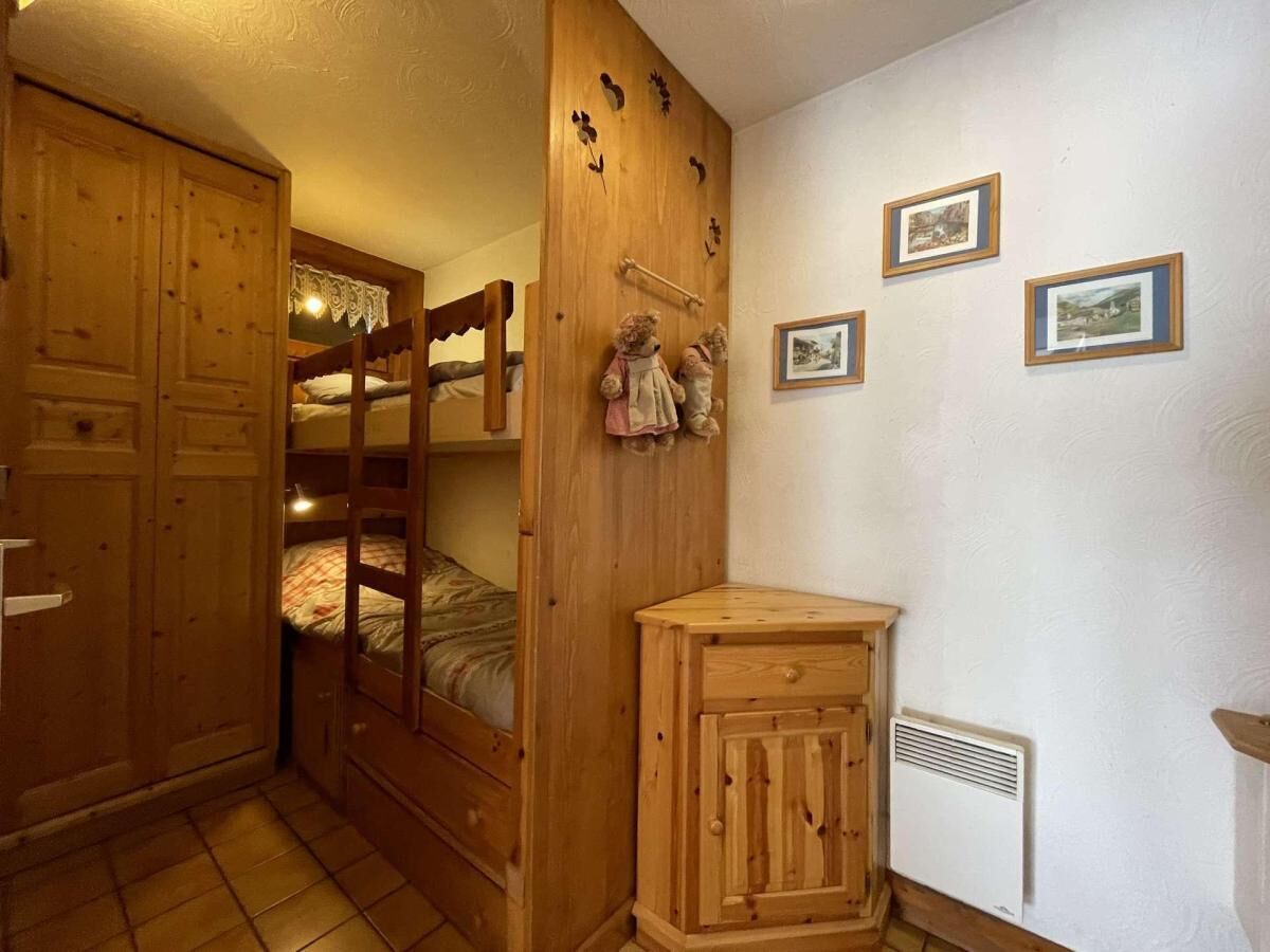 Une chambre avec un lit superposé, une armoire en bois et un petit meuble de rangement.