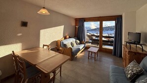 En hyggelig stue med sofa, spisebord og fjernsyn.
