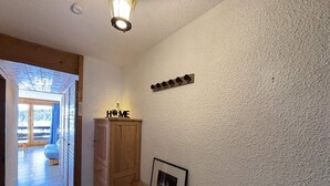 En gang med et træskab, et billede i ramme på væggen og et skilt med teksten 'HOME' over skabet.