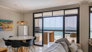 A modern living room with a large sliding glass door leading to a balcony overlooking the sea. - Beautiful Seaside Apartment With Barbecue Rig0102 (Florianópolis)