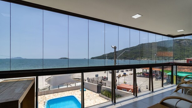 Ein Balkon mit Meerblick, einem Pool und Sitzgelegenheiten im Freien.