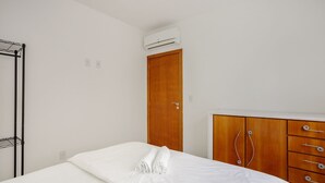 A bedroom with a bed, a wooden wardrobe, and an air conditioning unit. - Apt one Block sea 260m Praia dos Ingleses Rie0315 (Florianópolis)