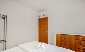 A bedroom with a bed, a wooden wardrobe, and an air conditioning unit. - Apt one Block sea 260m Praia dos Ingleses Rie0315 (Florianópolis)