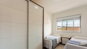 A bedroom with two beds, a sliding door, and a window with a view of buildings. - Apt 500m From Ingleses Beach, Floripa Rid3106 (Florianópolis)