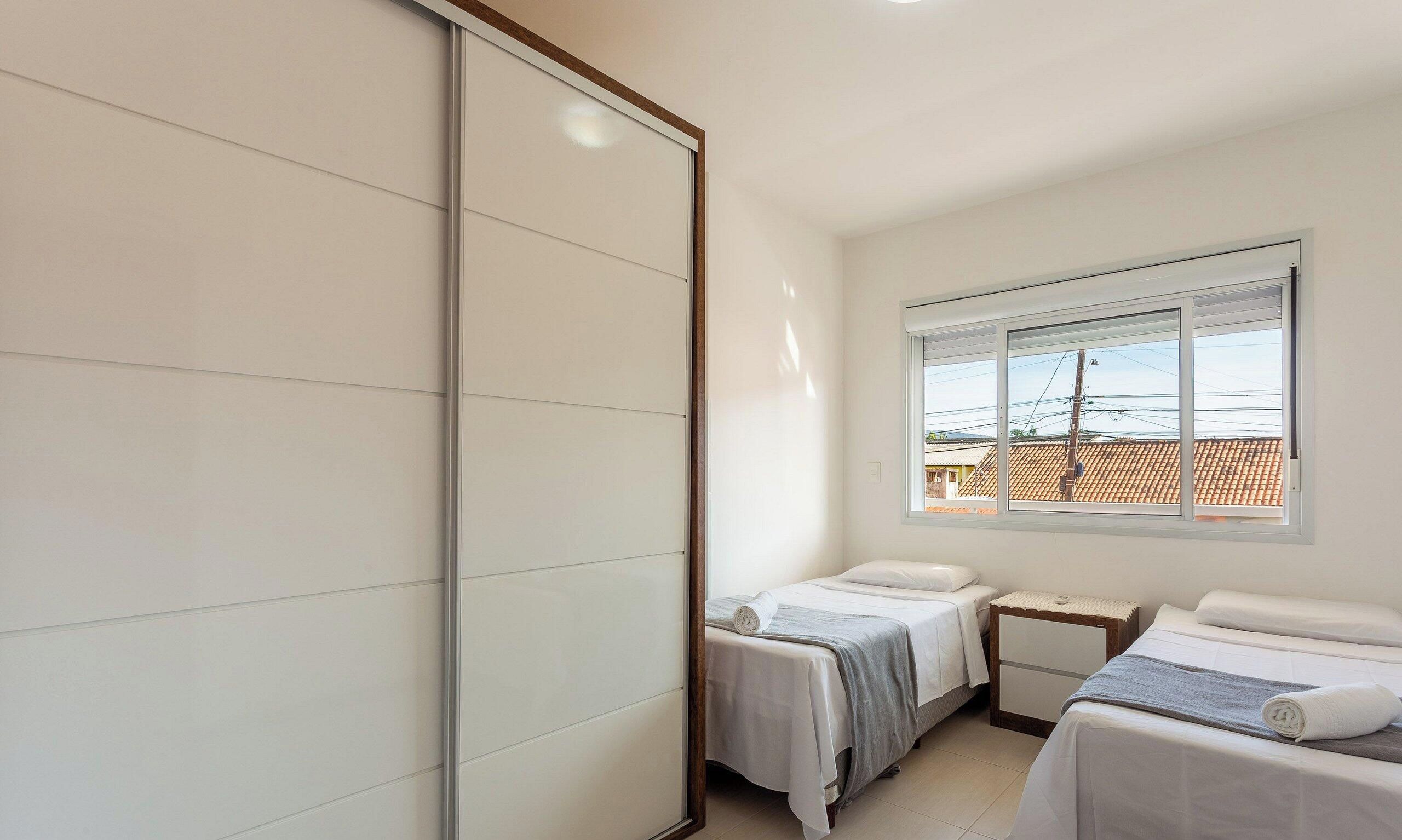 Una habitación de hotel con dos camas, una ventana con vistas a edificios y una puerta corrediza.
