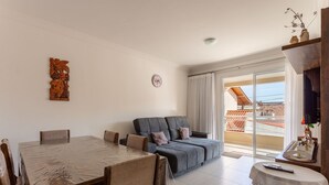 A living room with a sofa, a dining table, and a TV. - Apt 500m From Ingleses Beach, Floripa Rid3106 (Florianópolis)