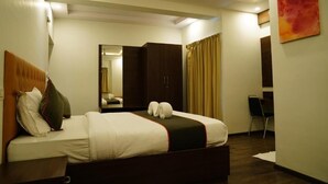 A hotel room with a bed, a wardrobe, a mirror, and a chair. - Suraksha Stay ITPL Hotel (Bengaluru)