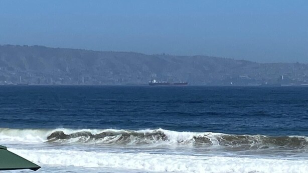 A coastal view with a ship in the distance and a city skyline on the horizon.