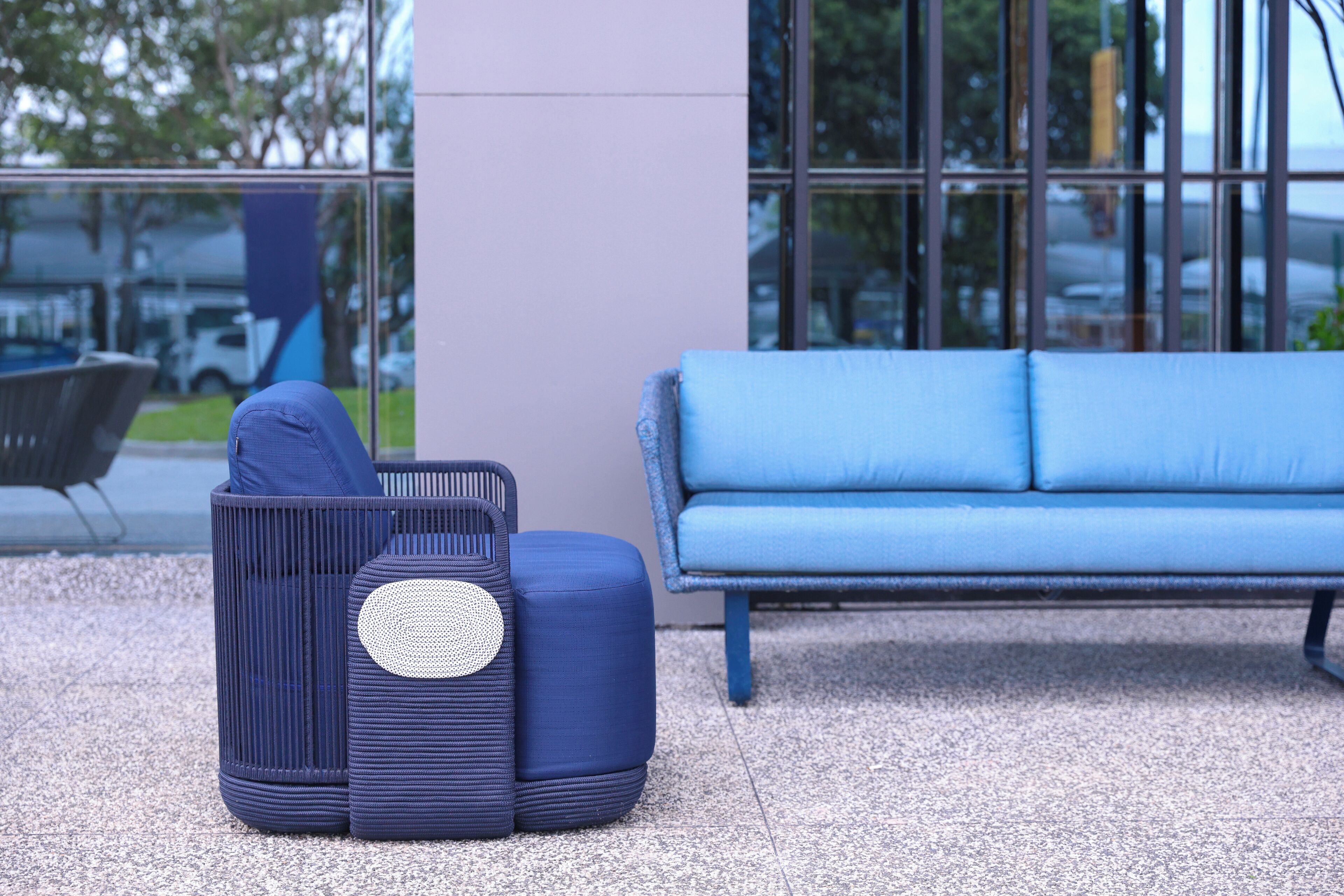 Un espace extérieur moderne avec des sièges, comprenant un canapé bleu et un pouf bleu à motifs en relief.