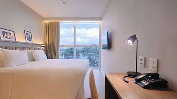 A hotel room with a bed, a desk, a telephone, and a television.