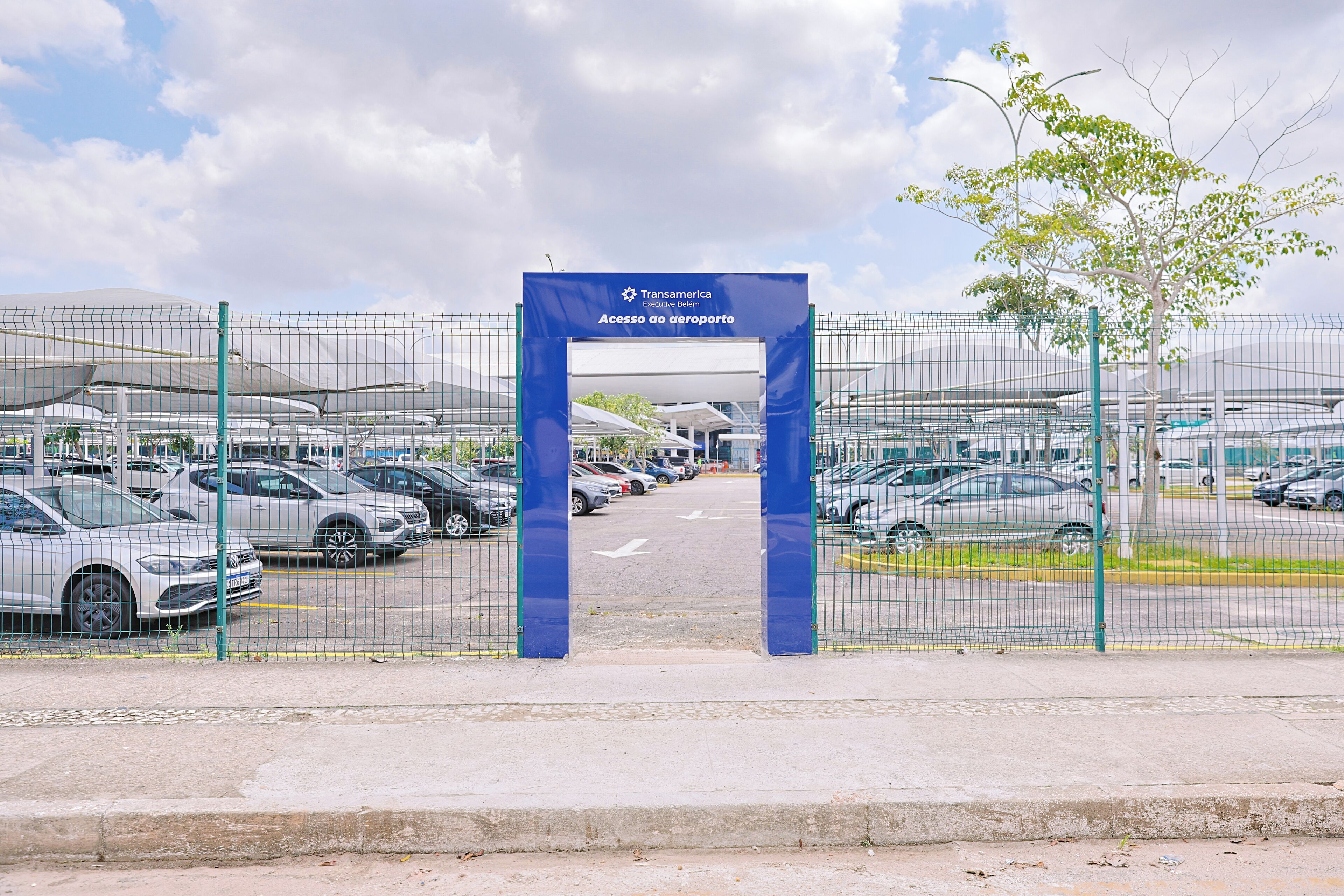 A parking area with a blue sign indicating access to an airport.