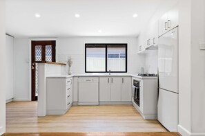 A modern kitchen with white cabinetry, a built-in dishwasher, a stove, and a refrigerator. - Strathdale Stay - Cozy & Pet Friendly (Strathdale)