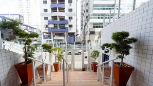 Een modern gebouw met een glazen gevel, buiten trappen en potplanten.