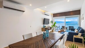 Un salon moderne avec une table à manger en bois, un canapé et un téléviseur fixé au mur.