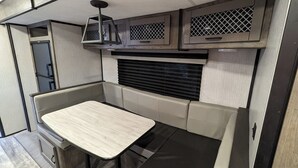 A compact kitchenette with a built-in stove, a small table, and overhead cabinets.