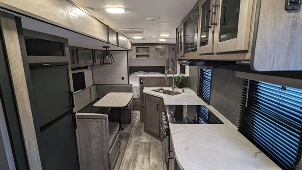 A compact RV kitchen with a sink, stove, and seating area.