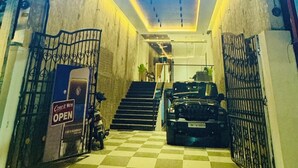 Exterior del hotel Vaigai Residency Business con un llamativo letrero iluminado, un acceso a cuadros y un camino de entrada con puerta de reja.