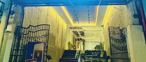 Exterior del hotel Vaigai Residency Business con un llamativo letrero iluminado, un acceso a cuadros y un camino de entrada con puerta de reja.